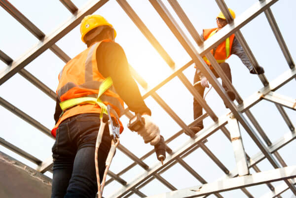Roofer drilling fixings on a metal standing-seam roof